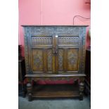 An Elizabethan Revival carved oak two door livery cupboard