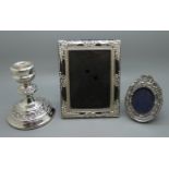 A silver candlestick and two photograph frames