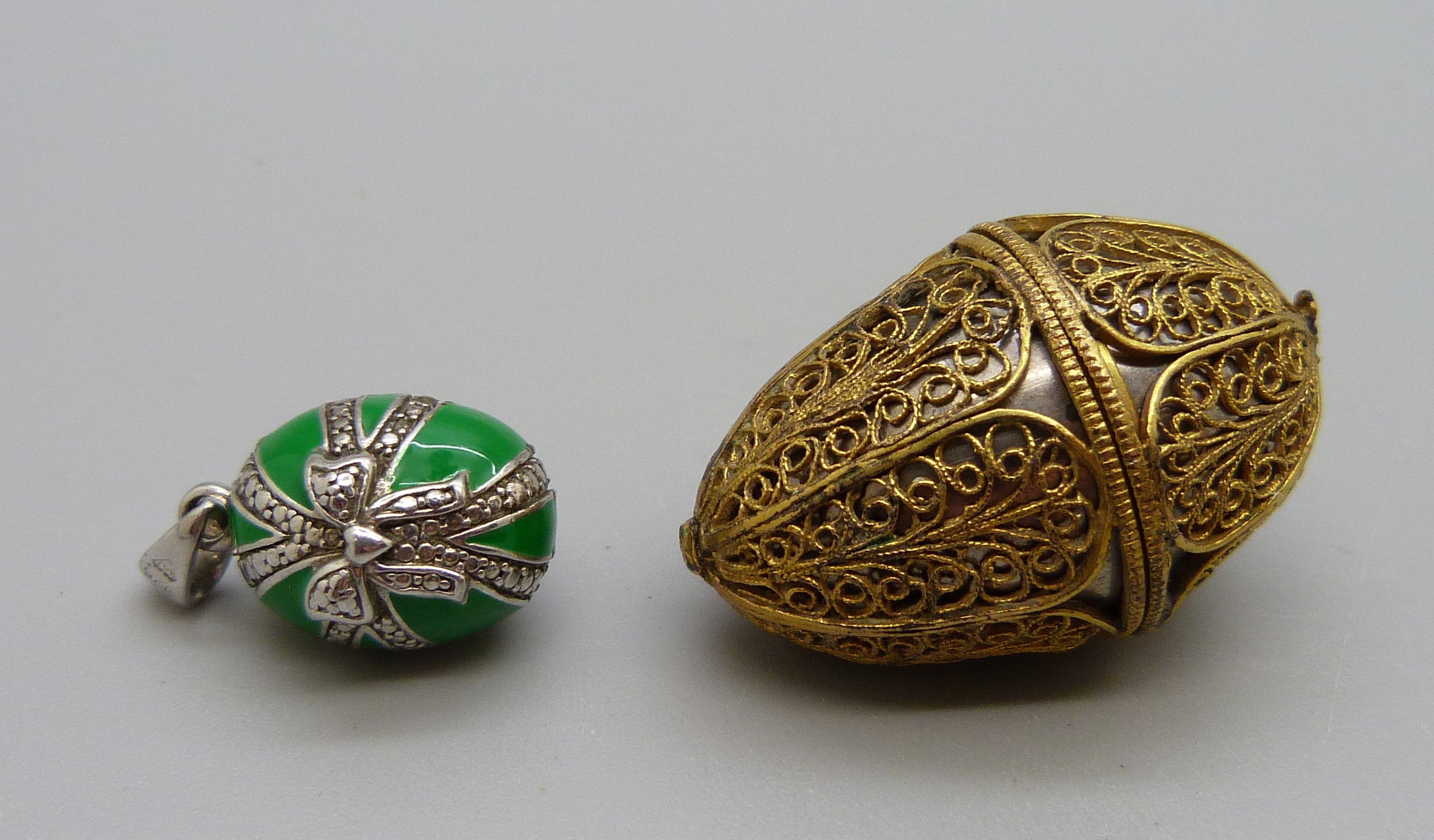A silver gilt filigree egg thimble holder, hinge requires repair and a silver mounted pendant