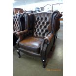 A chestnut brown leather Chesterfield wingback armchair