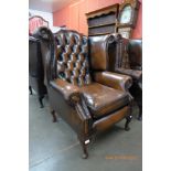 A chestnut brown leather Chesterfield wingback armchair