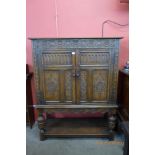 An Elizabethan Revival carved oak two door livery cupboard