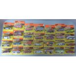 Twenty-eight Matchbox orange and yellow box model vehicles, all in blister packs