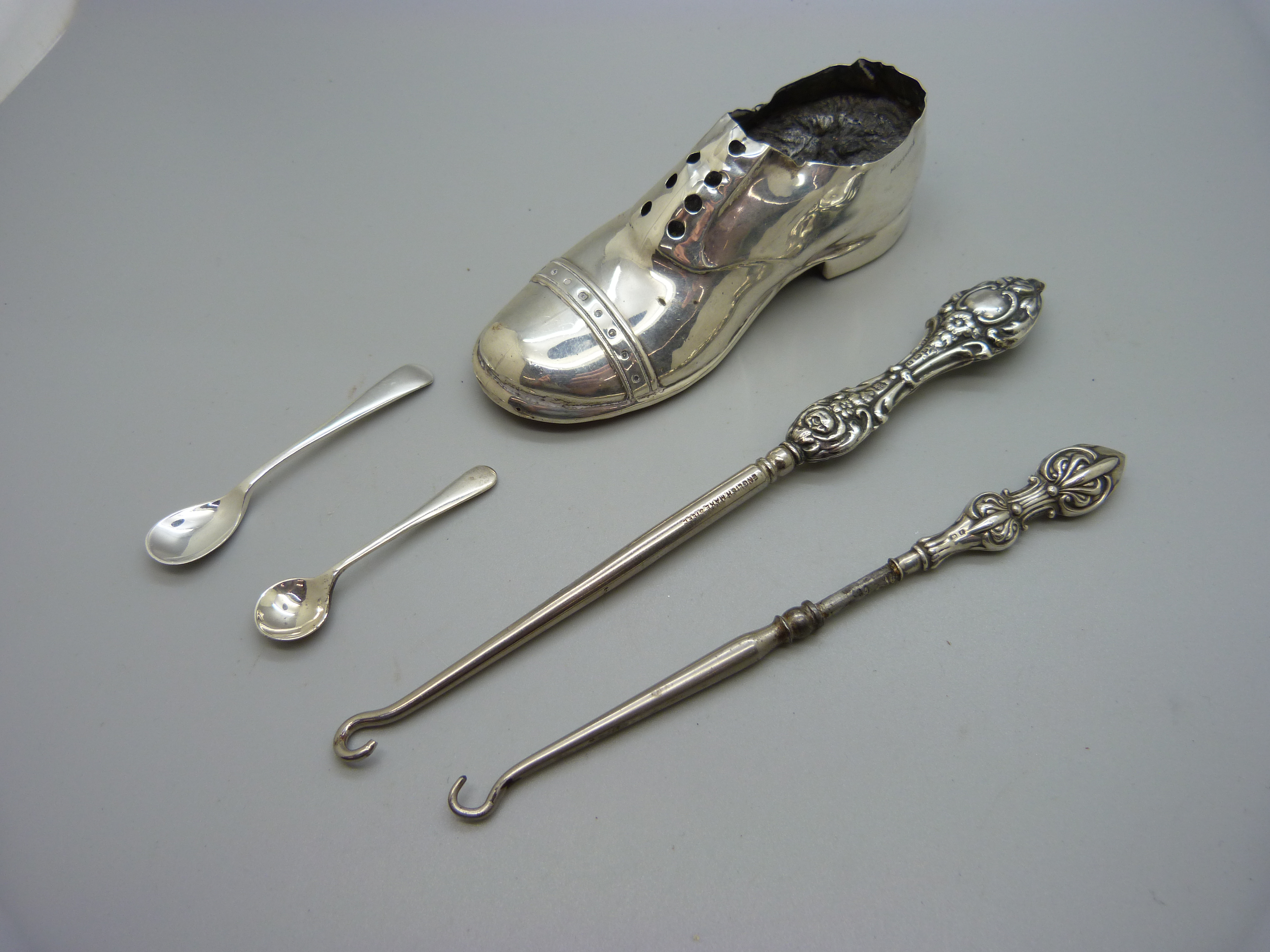 A novelty silver shoe pin cushion, a/f, two button hooks and two silver salt spoons