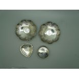 A pair of silver coin set dishes, a Victorian silver heart shaped dish and a circular silver pot