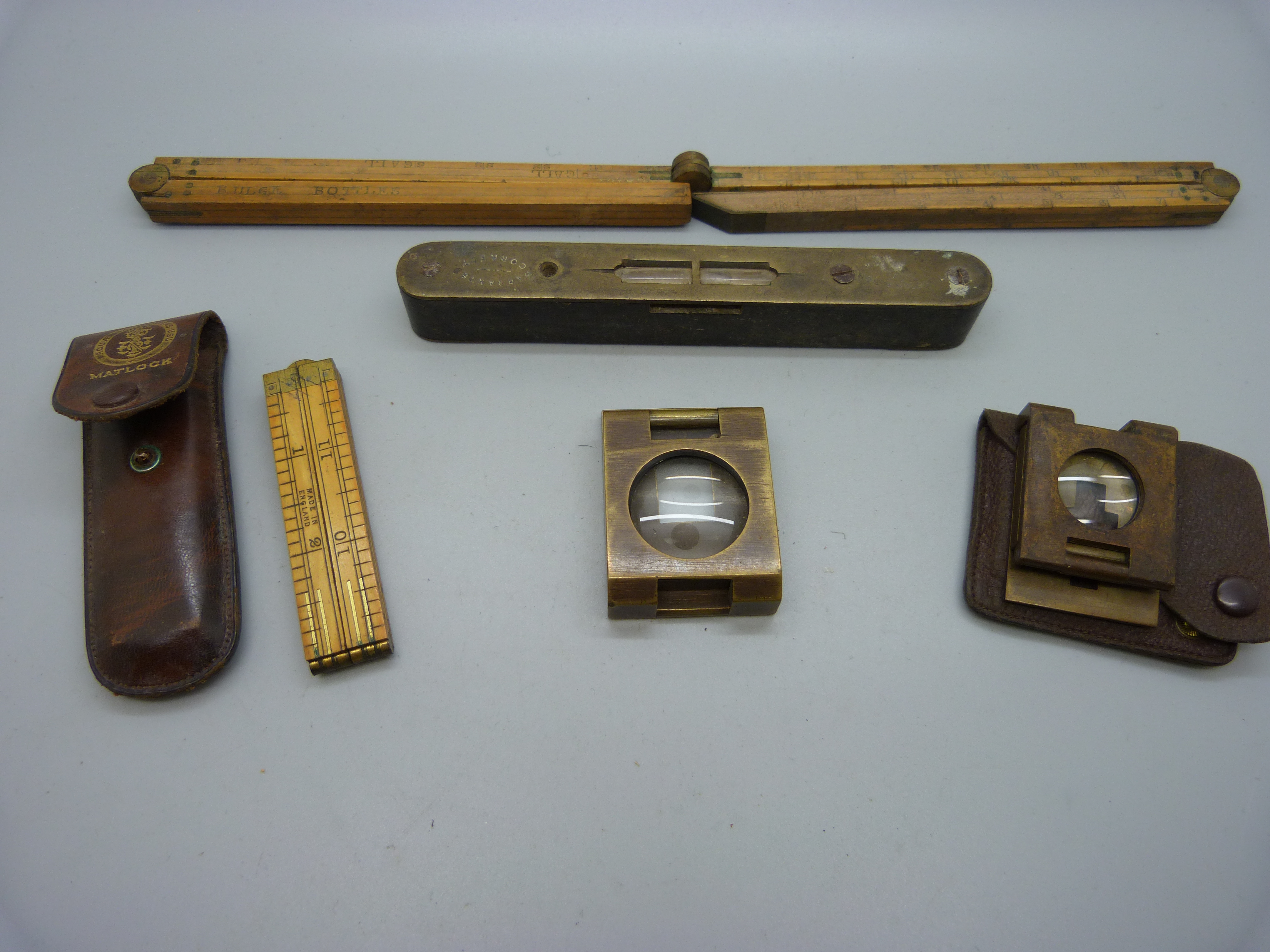 A folding ruler, a Coopers' gauge, two brass folding magnifying glasses and a spirit level