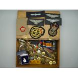 A collection of military uniform badges and buttons, a trench art letter opener, etc.