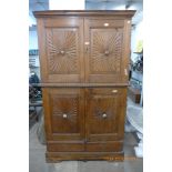An Indian carved hardwood four door cupboard, the doors carved with sunburst panels