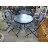 A circular metal and glass garden table and two chairs