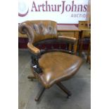A mahogany and tan leather revolving Captain's desk chair