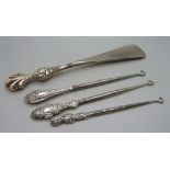 Three silver mounted button hooks and a shoe horn