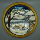 A framed Moorcroft charger, Winter Foxes in the Snow, 26cm