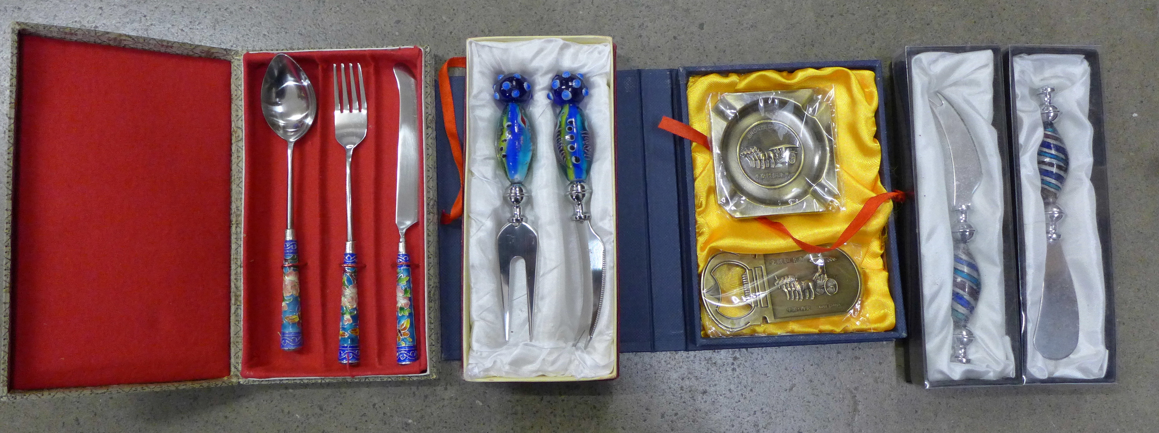 A glass handled cheese knife and butter knife, a similar set and ashtray and bottle opener **