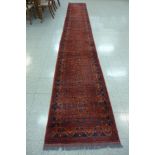 A Turkish hand knotted red ground runner, 582 x 80cms