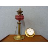 An Art Nouveau brass and cranberry glass oil lamp (converted to electricity) and a Metamec quartz