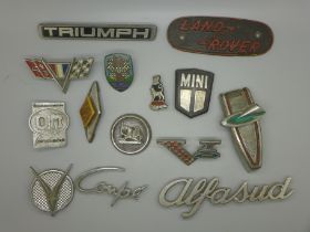 A collection of car badges including Mini, Alfa Sud, Land Rover plaque, old Volkswagen, Renault
