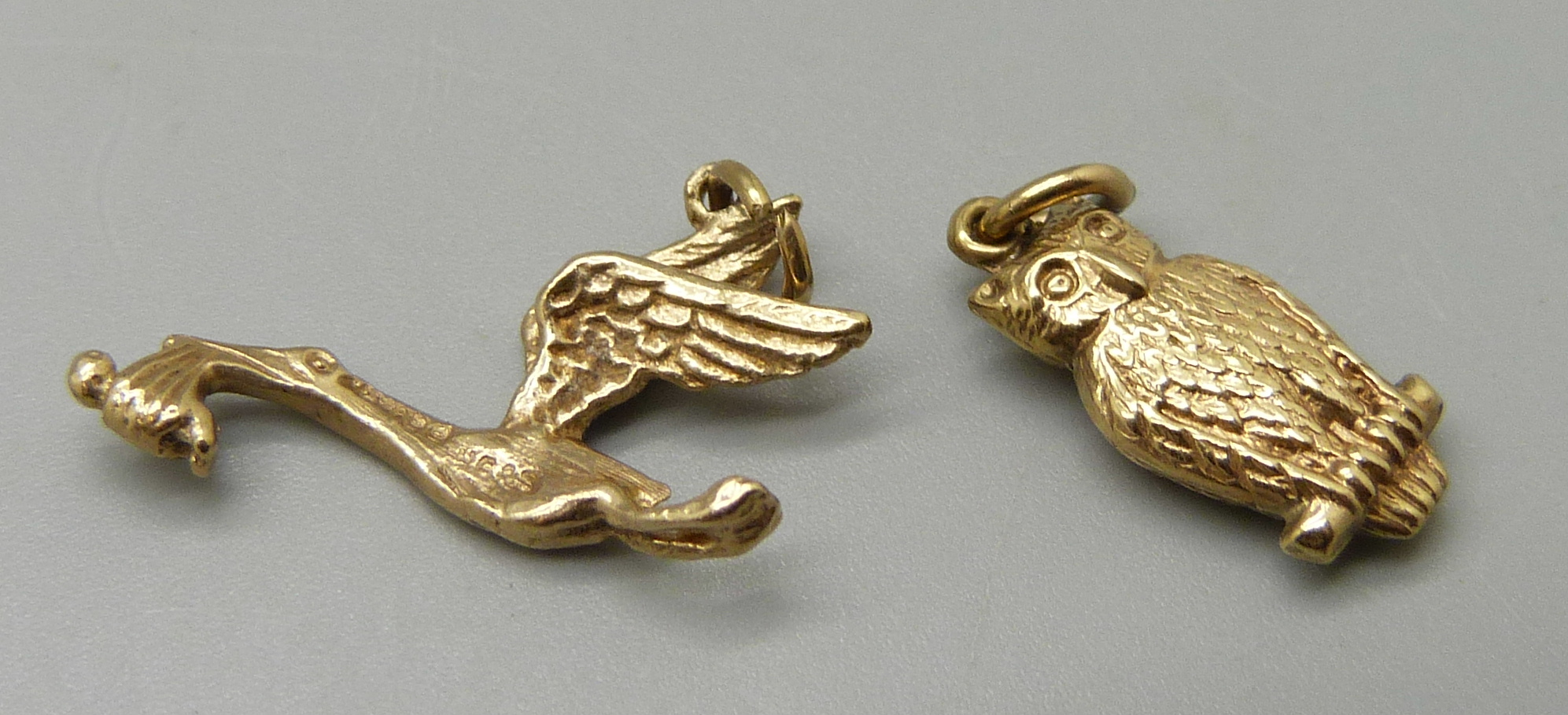 A 9ct gold stork and baby charm and a 9ct gold owl charm, 1.9g