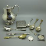 Plated ware including a jug, flatware, a cigarette box, a silver spoon, 25g, and two crowns