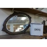 A carved oak framed mirror and an enamelled bread bin