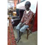 A life size Goldscheider style hand painted fibreglass figure of a seated young boy