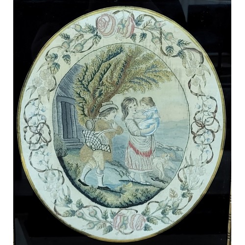 A Regency oval silkwork, depicting a young couple with baby, within a border of flowers and swags,