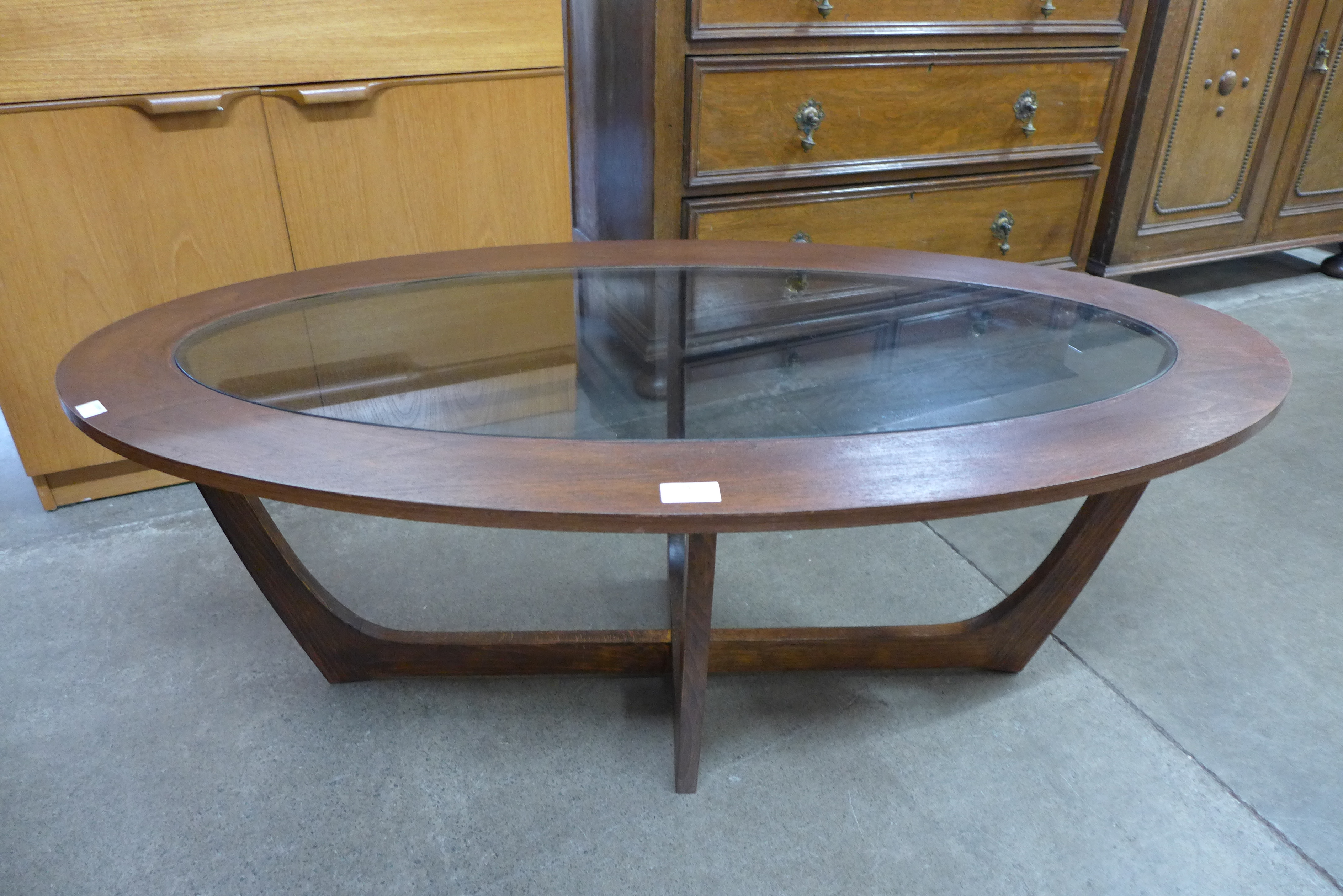 An oval teak and glass coffee table