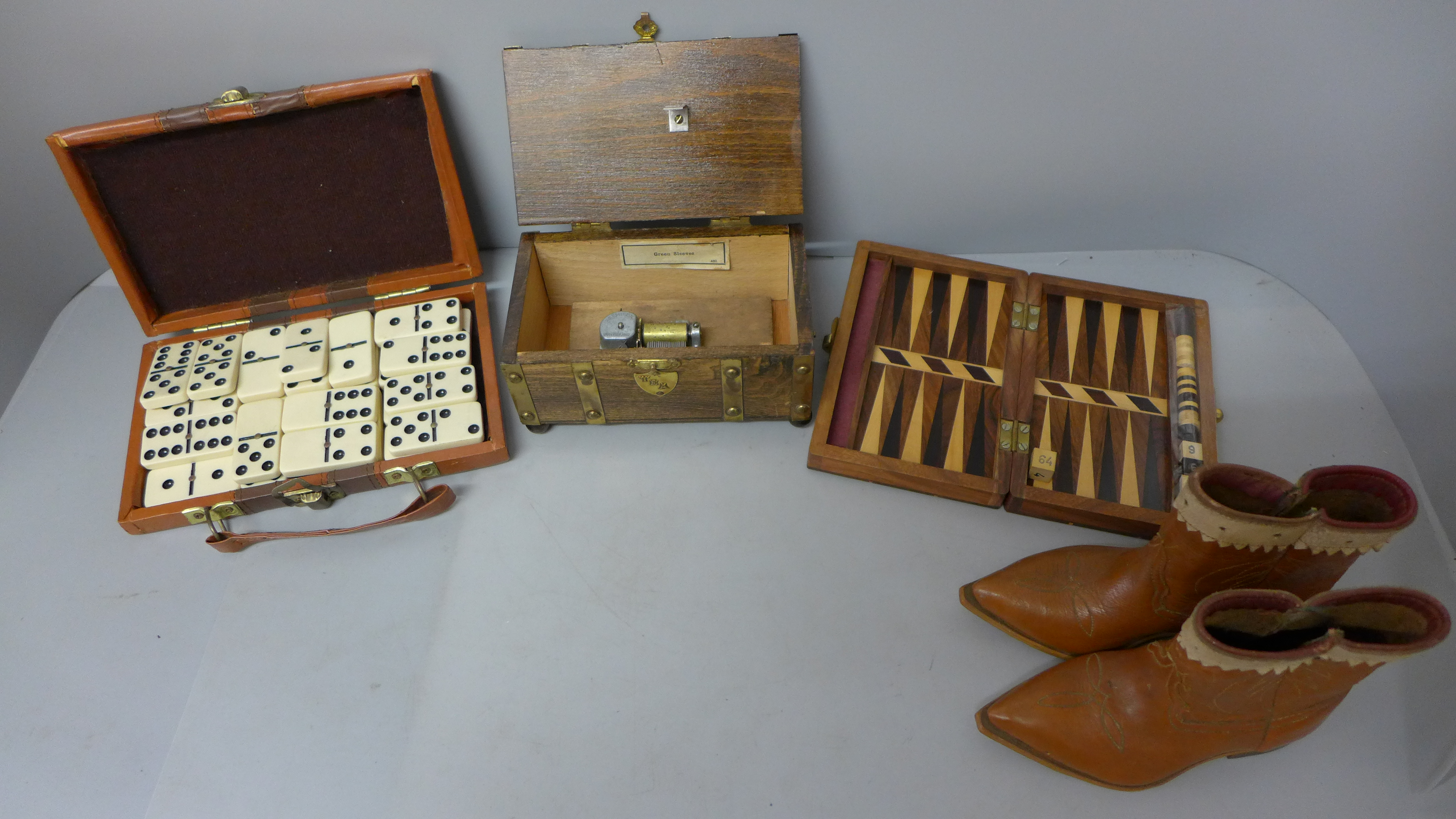 Travel dominoes, a musical box, travel backgammon and a small pair of leather cowboy boots