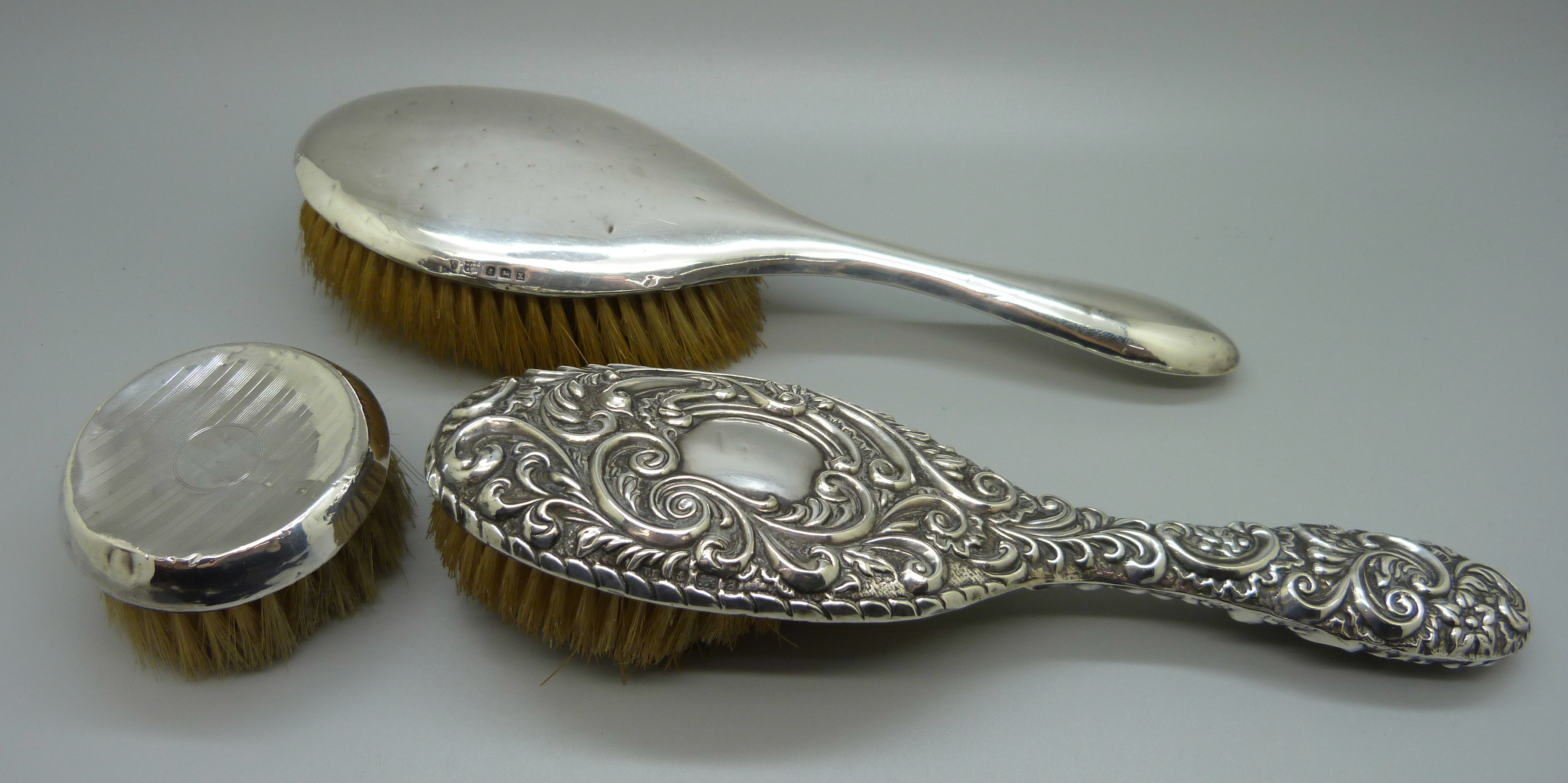 Three silver backed brushes, a/f