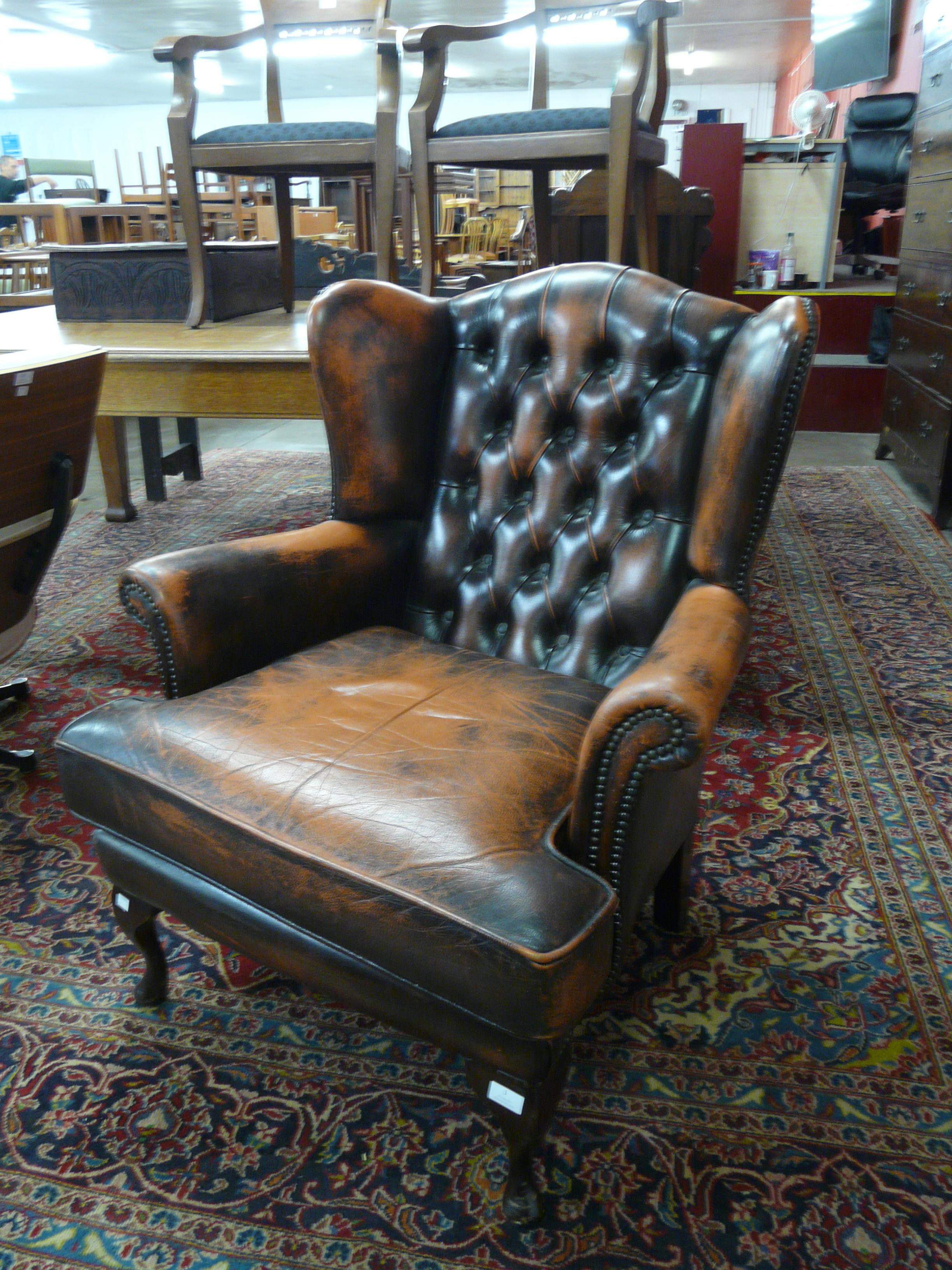 A tan leather Chesterfield wingback armchair