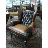 A tan leather Chesterfield wingback armchair