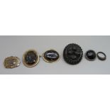 A large carved jet brooch, small chips to the rim, a mourning brooch, three other brooches and a jet
