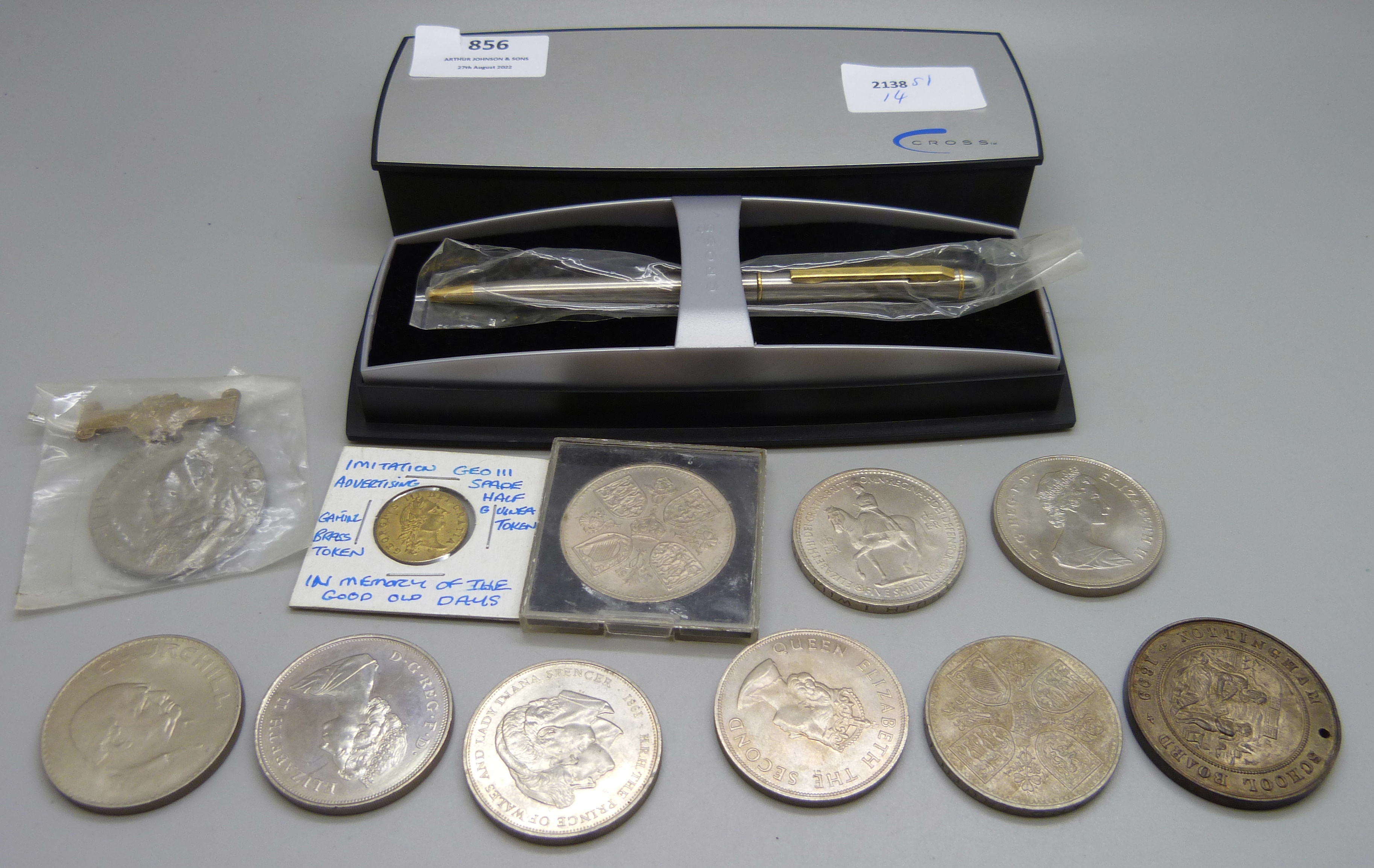 A collection of commemorative coins and a Cross pen