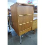 A teak chest of drawers on chrome stand