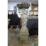 A concrete garden figural cherub bird bath