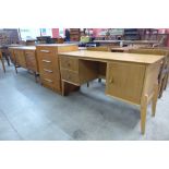 A Meredew walnut desk, a teak chest of drawers and sideboard, a/f