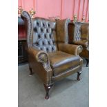 A chestnut brown leather Chesterfield wingback armchair