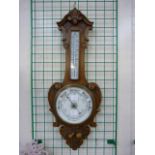 An Edward VII carved oak aneroid barometer