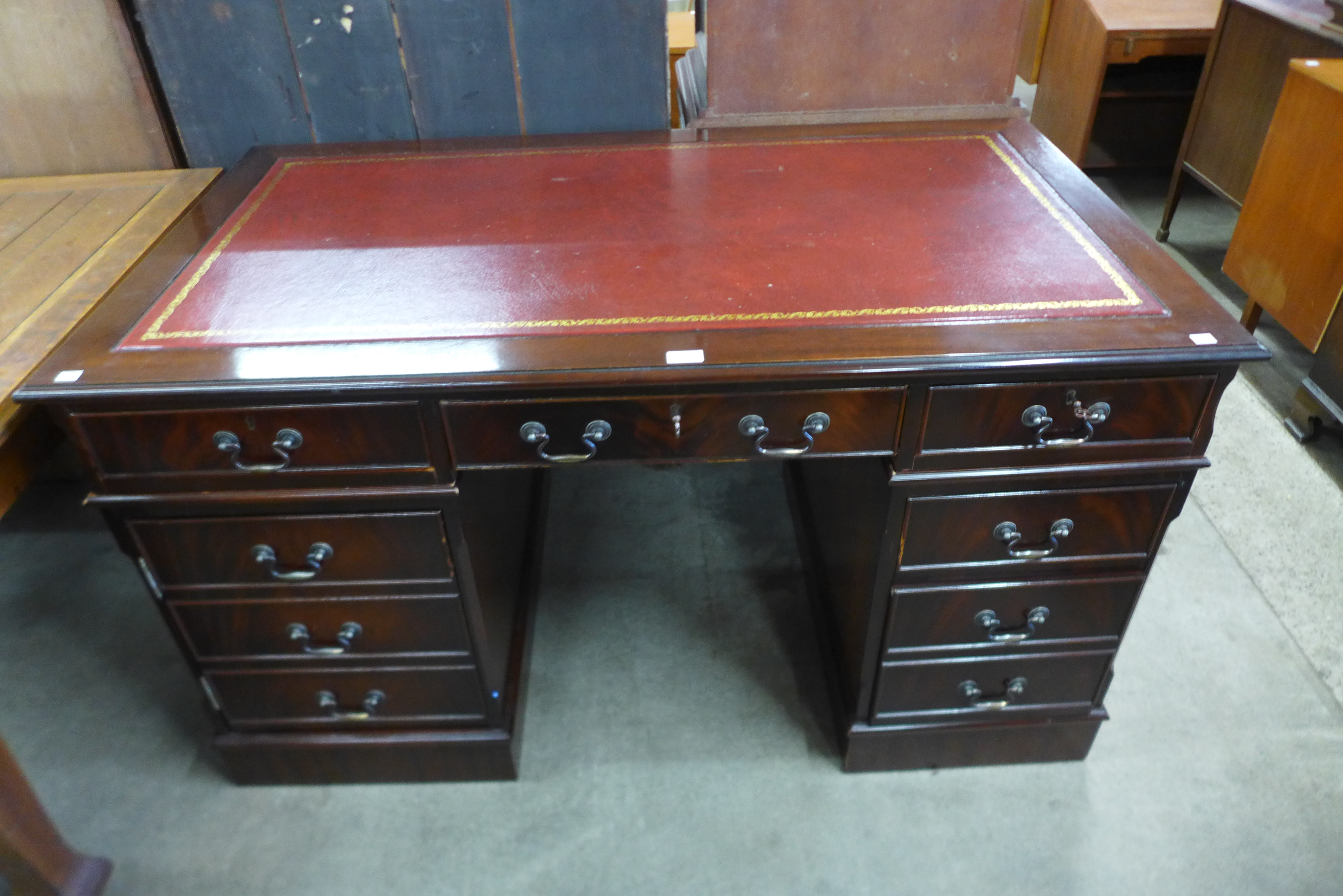 A mahogany and red leather topped pedestal desk