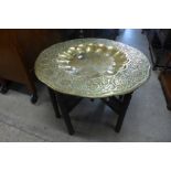 An Indian carved wood and brass topped folding occasional table