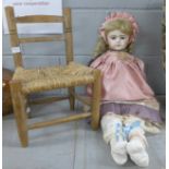 A large antique reproduction bisque head character doll on woven wooden chair, 76cm **PLEASE NOTE