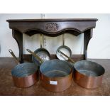 A set of five graduated copper coated and brass saucepans with pan rack