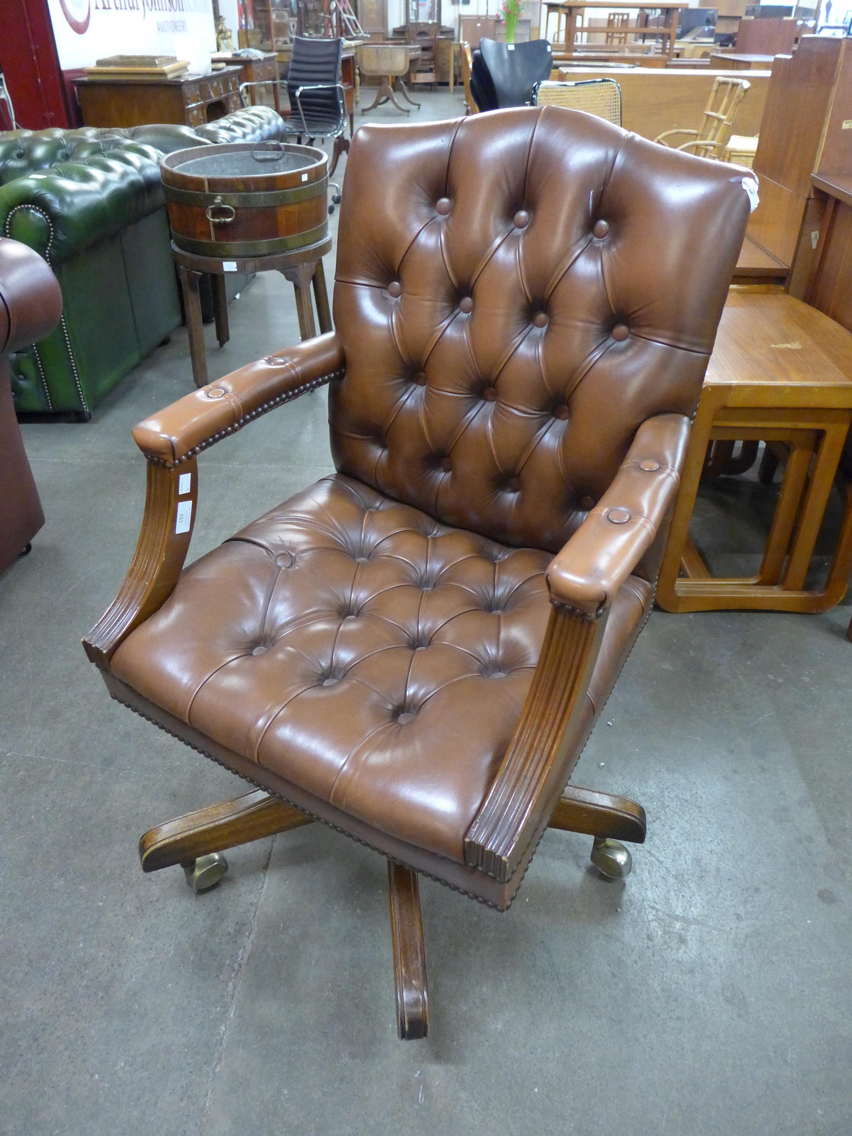 A mahogany and tan leather revolving desk chair