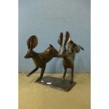 A metal figure of two running hares