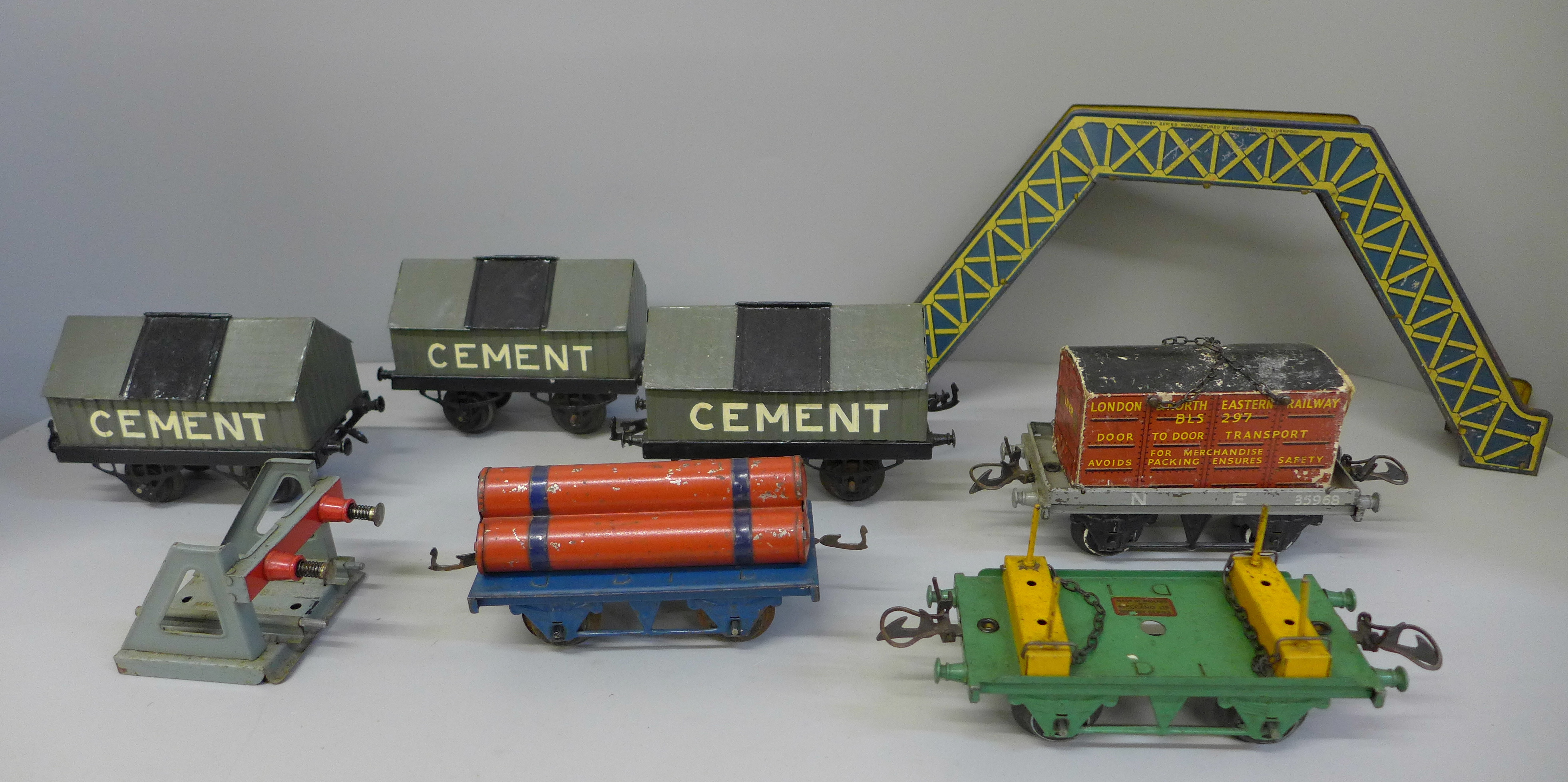 Six Hornby 0 gauge pre-war wagons, a tinplate footbridge and a buffer stop