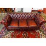An oxblood red leather three seater settee