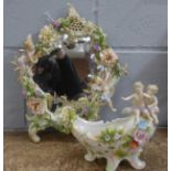 A continental porcelain mirror, flower encrusted and with cherubs playing musical instruments,