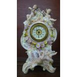 A continental porcelain figural clock, with three cherubs and decorated with flowers