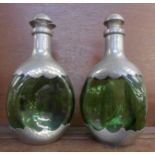 A pair of green glass and pewter covered decanters