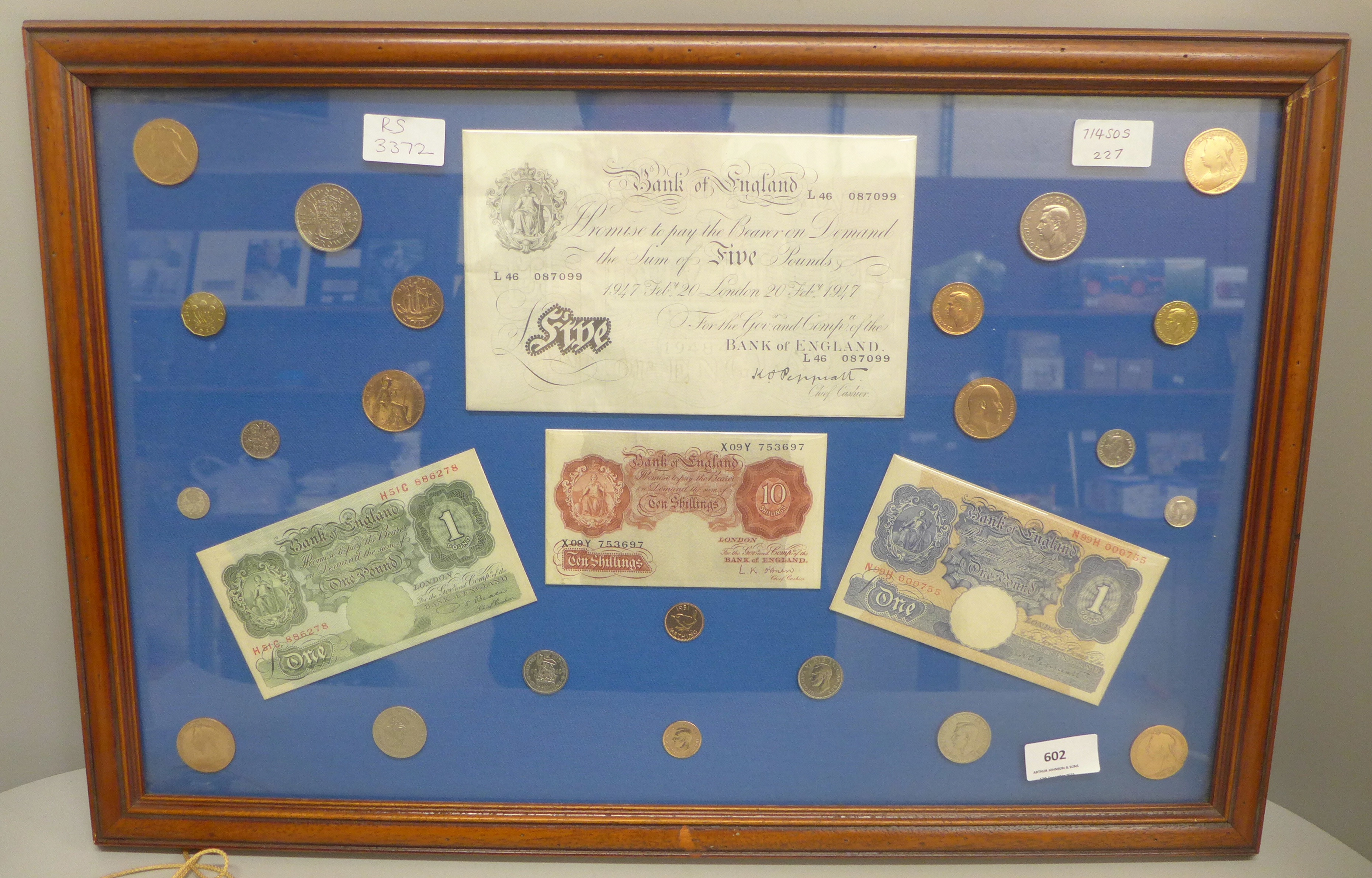 A framed Five Pounds white bank note, two £1 notes, ten shillings note and other coins
