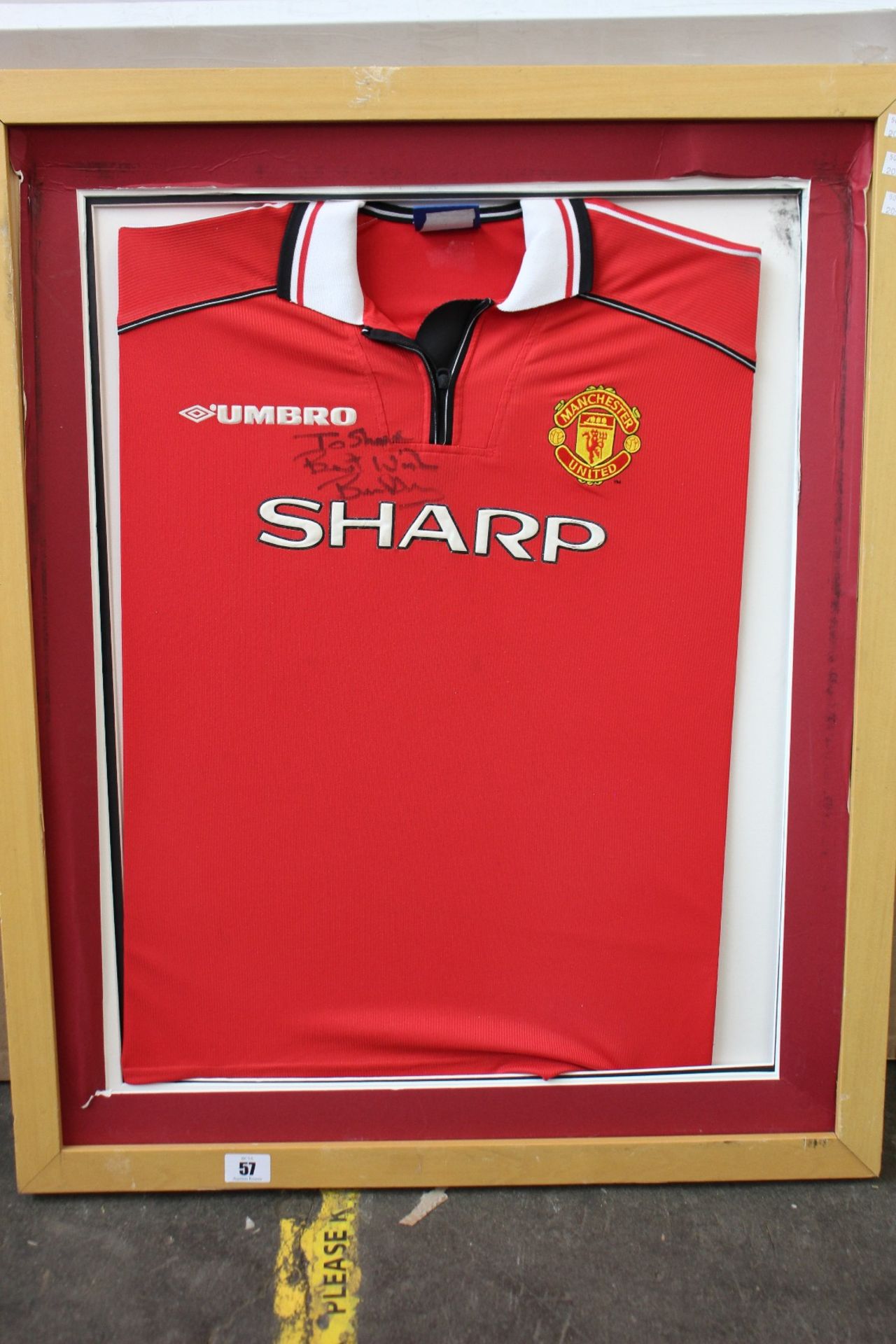 A pre-owned Brian Robson signed Man United football shirt (Item in a damaged frame, may be